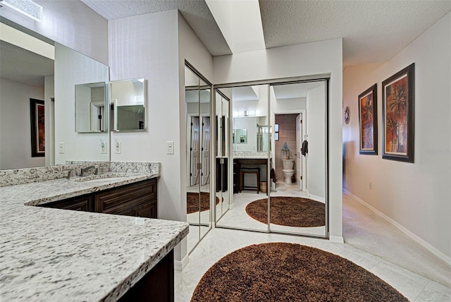 bathroom with vanity, a textured ceiling, and toilet