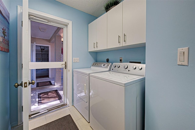 washroom featuring cabinets, washing machine and dryer, and light tile patterned floors