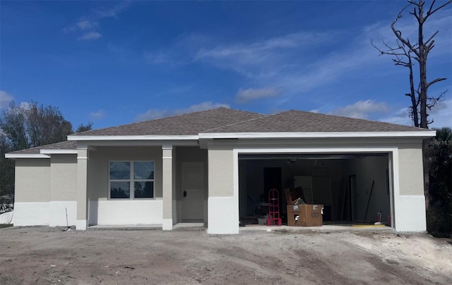 view of front of house featuring roof with shingles, an attached garage, and stucco siding