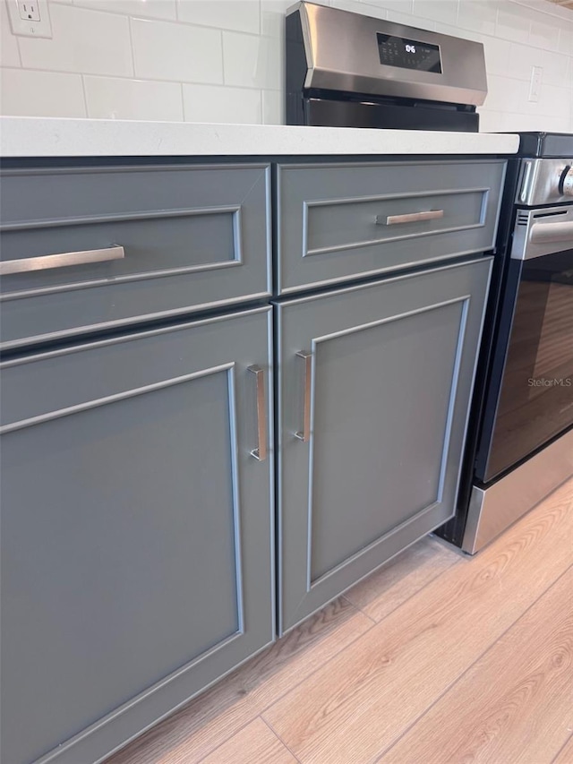 kitchen view of gray cabinetry, stainless steel range oven, and light countertops