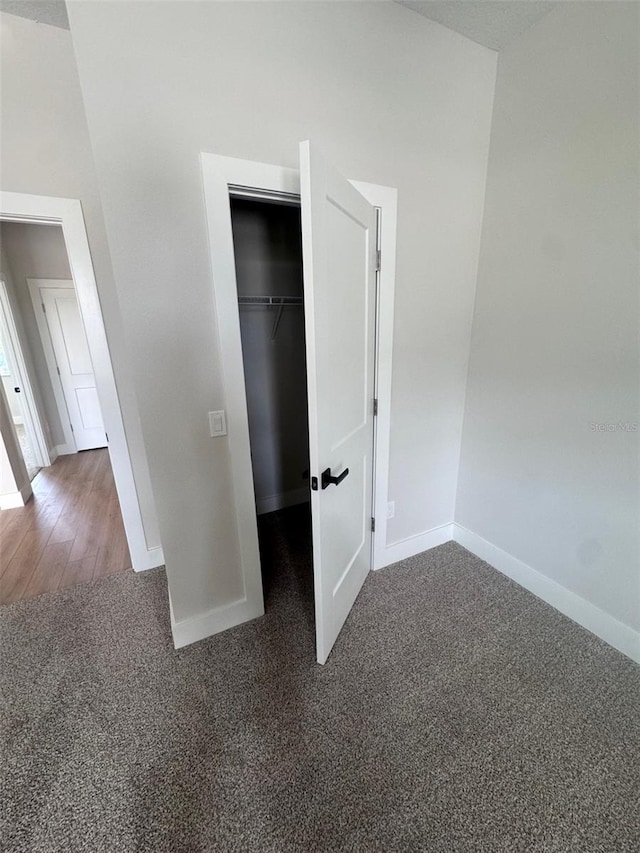 unfurnished bedroom featuring baseboards, carpet flooring, a closet, and a spacious closet