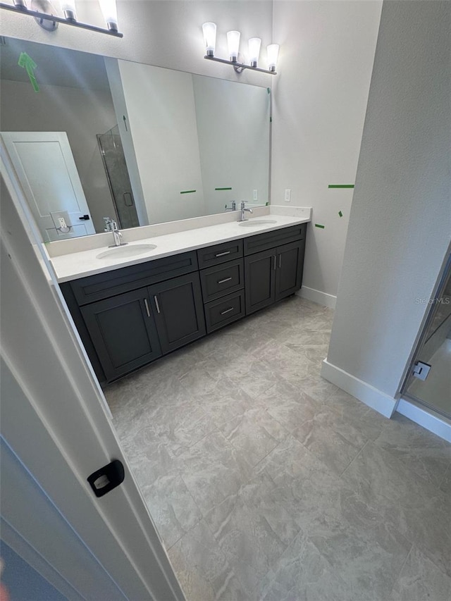 bathroom with a stall shower, double vanity, and baseboards
