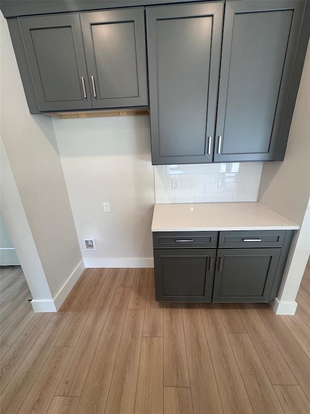 laundry area featuring baseboards and light wood-type flooring