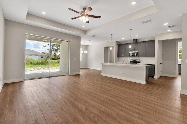 2814 Vogler Ln, North Port, FL 34286 - unfurnished living room featuring a raised ceiling, plenty of natural light, a ceiling fan, light wood finished floors, and recessed lighting