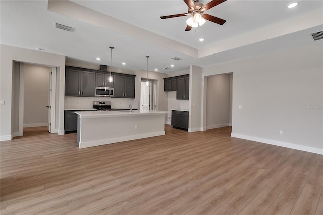 2814 Vogler Ln, North Port, FL 34286 - kitchen with appliances with stainless steel finishes, light wood-type flooring, open floor plan, a ceiling fan, and an island with sink