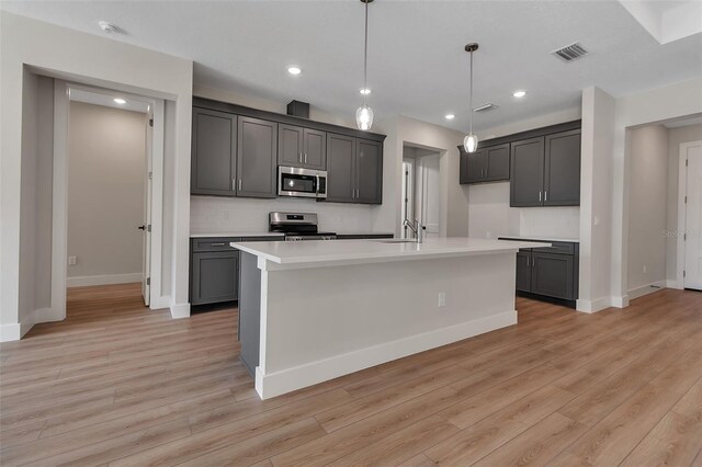 2814 Vogler Ln, North Port, FL 34286 - kitchen with appliances with stainless steel finishes, light wood-style floors, light countertops, a center island with sink, and tasteful backsplash