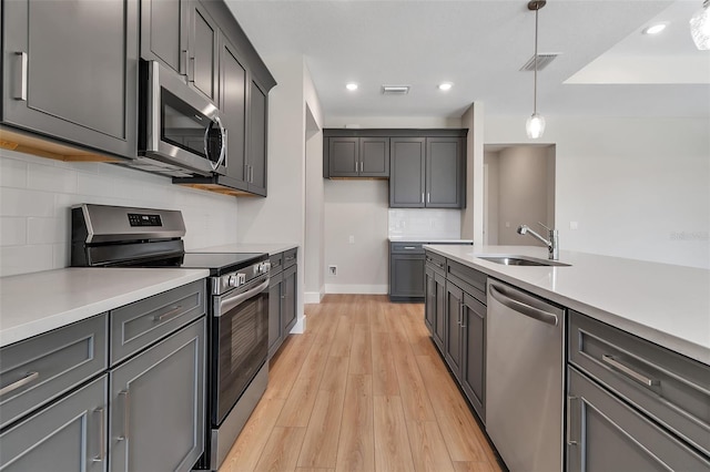 2814 Vogler Ln, North Port, FL 34286 - kitchen with stainless steel appliances, pendant lighting, tasteful backsplash, light wood-style flooring, and light countertops