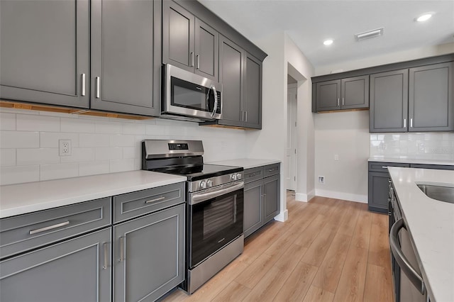 2814 Vogler Ln, North Port, FL 34286 - kitchen featuring appliances with stainless steel finishes, decorative backsplash, light wood finished floors, light countertops, and recessed lighting