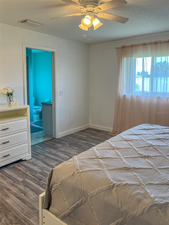 bedroom with dark wood-type flooring, ceiling fan, and ensuite bathroom