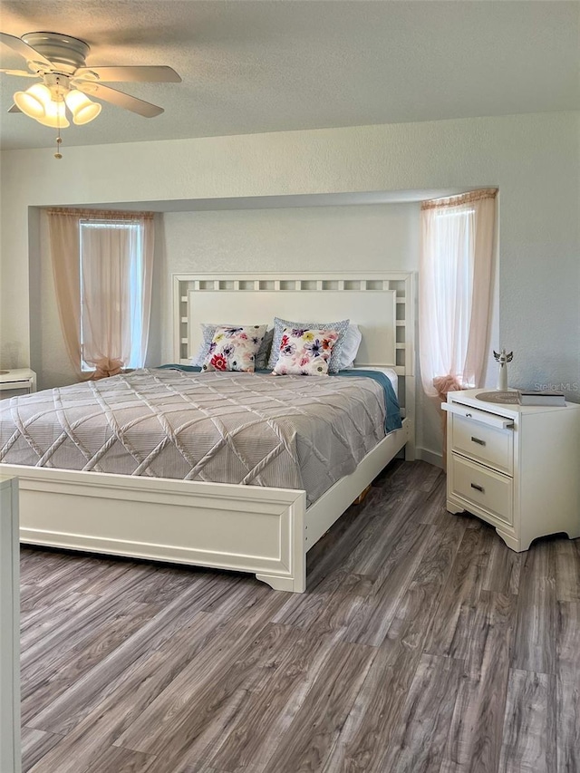 bedroom with dark hardwood / wood-style flooring and ceiling fan