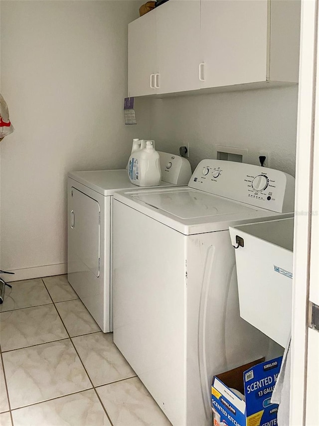 clothes washing area featuring cabinets, sink, washer and dryer, and light tile patterned floors