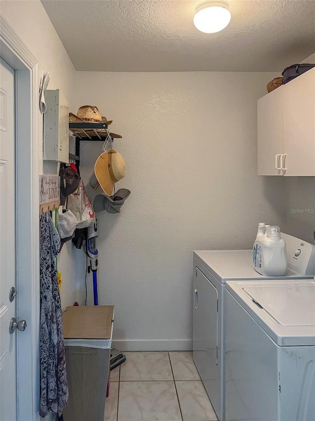 laundry area featuring cabinets, light tile patterned floors, a textured ceiling, and independent washer and dryer