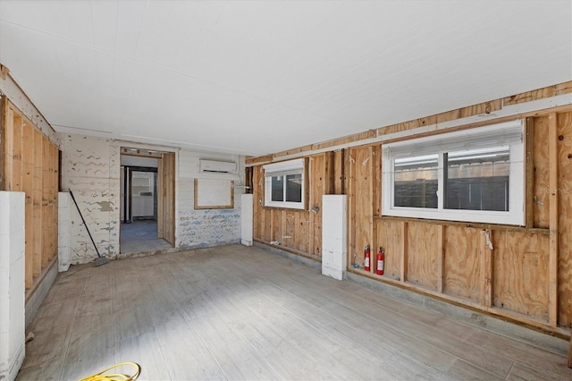 empty room featuring wooden walls, a wall unit AC, and light wood-type flooring