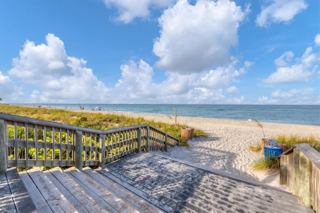 wooden deck featuring a water view and a view of the beach