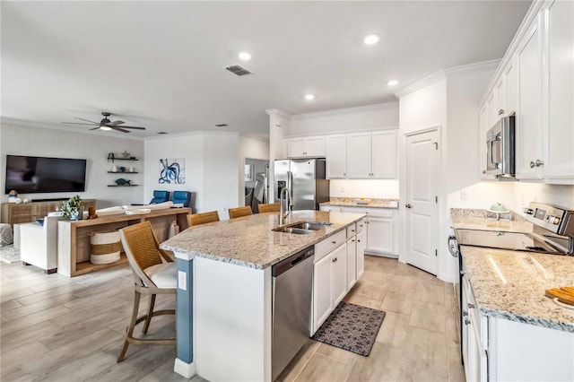 24269 Spartina Dr, Venice, FL 34293 - kitchen featuring white cabinetry, a kitchen breakfast bar, light stone counters, stainless steel appliances, and a center island with sink