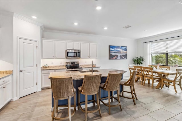 24269 Spartina Dr, Venice, FL 34293 - kitchen featuring white cabinetry, sink, a center island with sink, and appliances with stainless steel finishes
