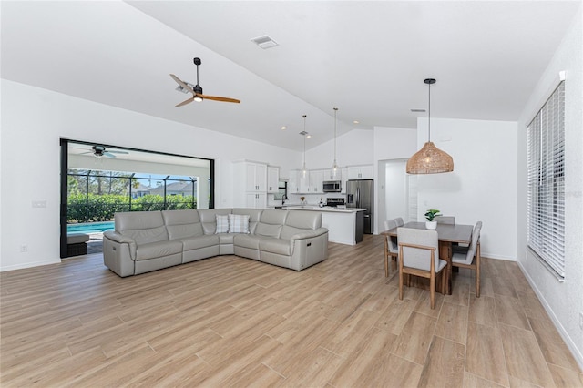 living room featuring light wood finished floors, visible vents, ceiling fan, baseboards, and high vaulted ceiling