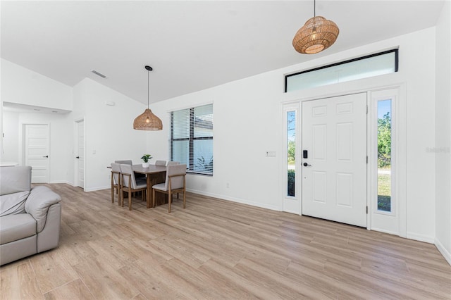 foyer entrance featuring visible vents, baseboards, lofted ceiling, and light wood-style floors