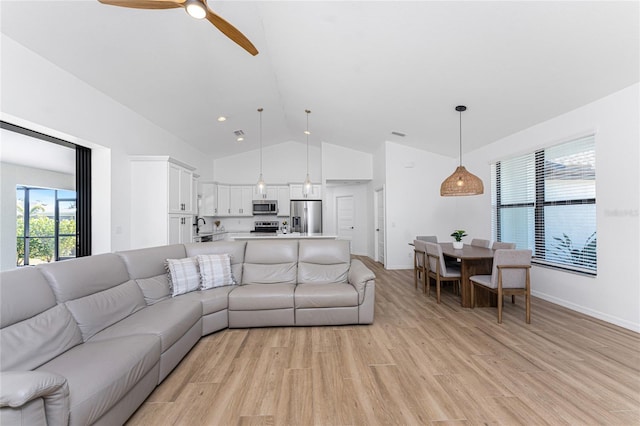 living room with ceiling fan, high vaulted ceiling, sink, and light hardwood / wood-style flooring