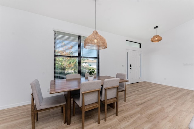 dining space featuring baseboards and light wood finished floors