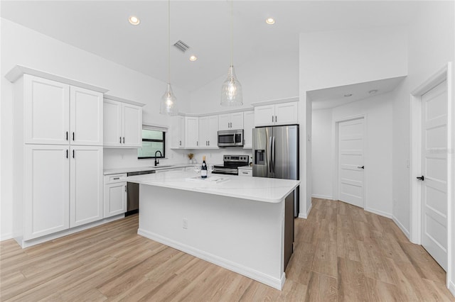 kitchen featuring light stone counters, decorative light fixtures, stainless steel appliances, a kitchen island with sink, and white cabinets