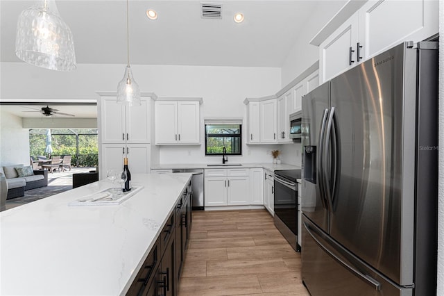 kitchen with white cabinetry, stainless steel appliances, decorative light fixtures, and sink