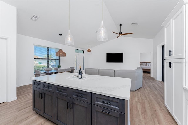 kitchen featuring lofted ceiling, white cabinets, light wood-style flooring, and visible vents