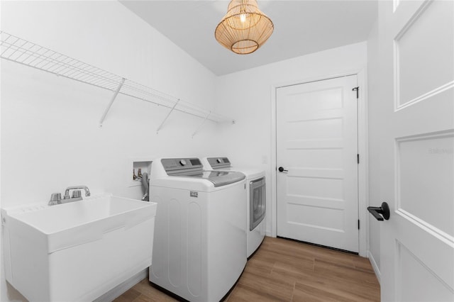 laundry area featuring sink, washing machine and clothes dryer, and light hardwood / wood-style floors