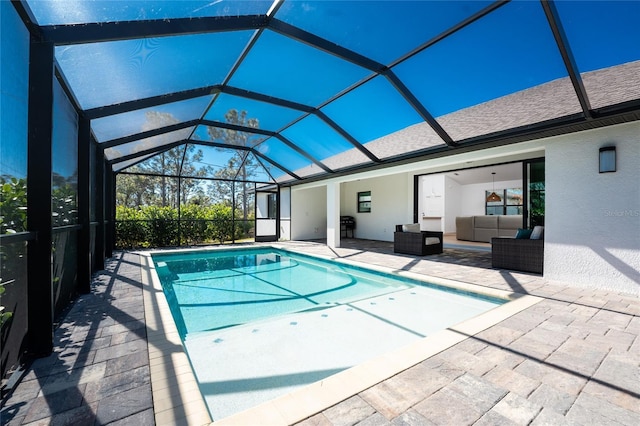 view of pool featuring a patio, an outdoor hangout area, and glass enclosure