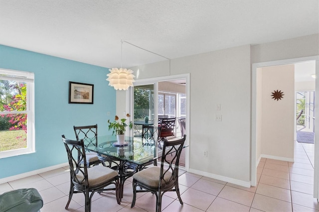 dining room with light tile patterned floors, a textured ceiling, plenty of natural light, and baseboards