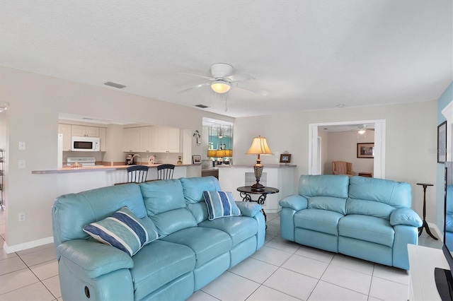 living room featuring a ceiling fan, visible vents, baseboards, and light tile patterned flooring