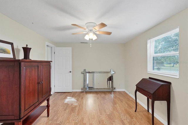 workout area with a ceiling fan, light wood-type flooring, and baseboards