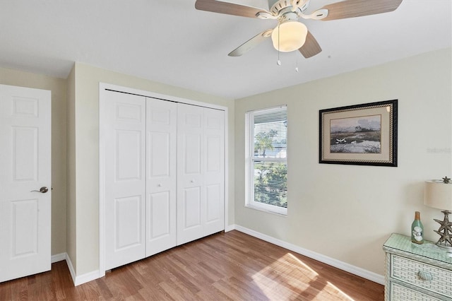 unfurnished bedroom with ceiling fan, a closet, wood finished floors, and baseboards