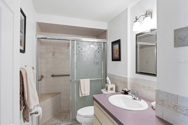 full bathroom with a textured ceiling, vanity, a shower stall, and toilet