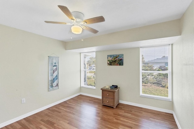 empty room featuring ceiling fan, baseboards, a wealth of natural light, and wood finished floors