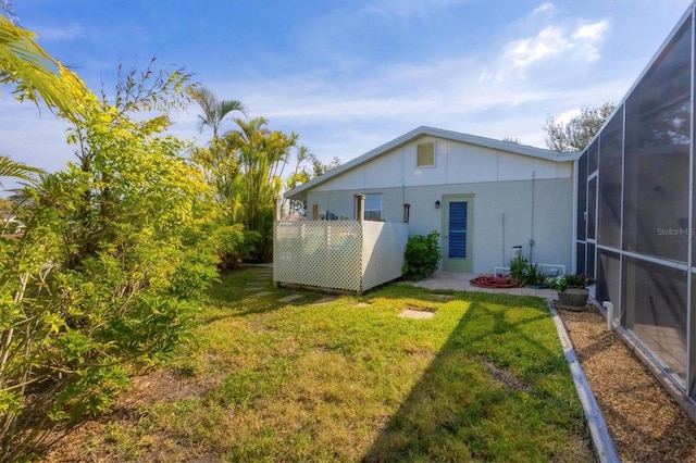 back of house with a lanai, a yard, and a patio