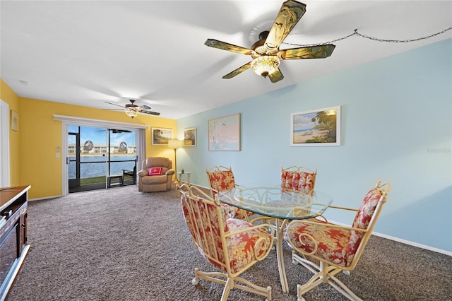 dining area with a water view, ceiling fan, and carpet floors