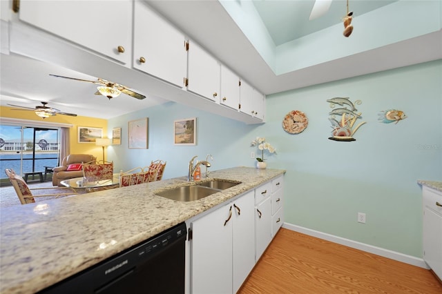 kitchen featuring black dishwasher, a water view, light wood-style flooring, white cabinets, and a sink