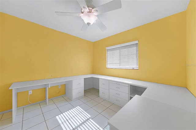 office space with a ceiling fan, light tile patterned flooring, and built in desk