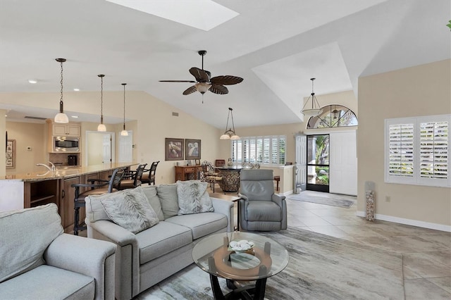 living room with lofted ceiling with skylight, light tile patterned floors, and ceiling fan