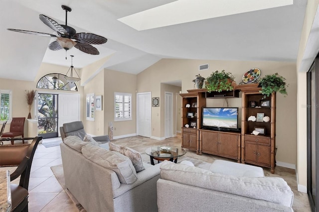 living room with ceiling fan, light tile patterned floors, a wealth of natural light, and vaulted ceiling with skylight