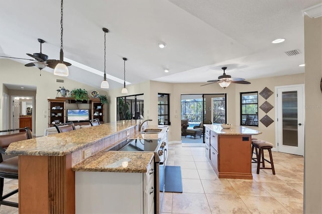 kitchen featuring a large island, pendant lighting, electric stove, a kitchen breakfast bar, and light stone countertops