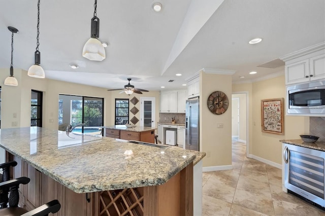 kitchen with a spacious island, wine cooler, hanging light fixtures, stainless steel appliances, and white cabinets