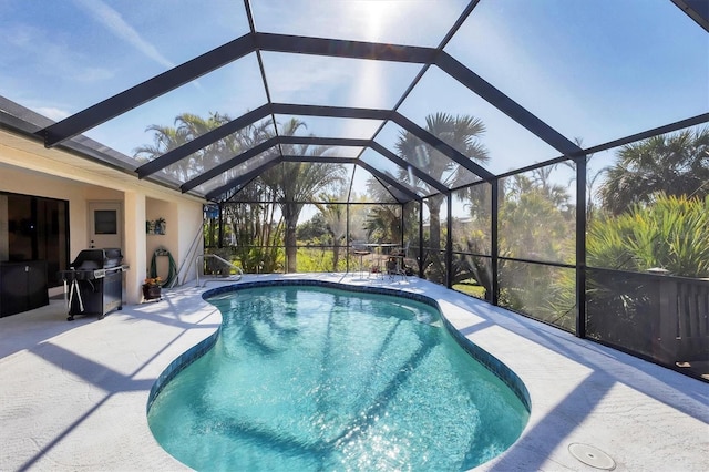 view of pool featuring area for grilling, a patio, and glass enclosure