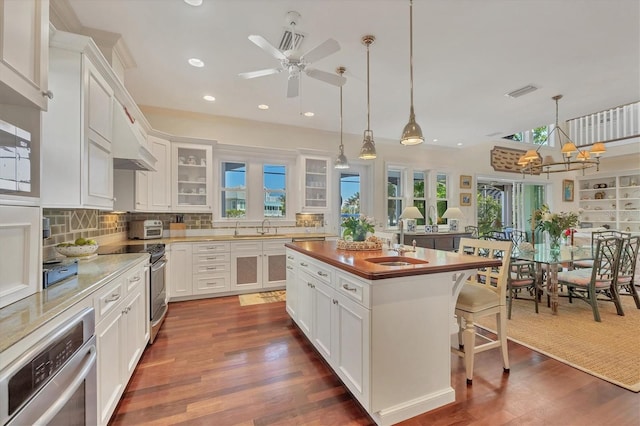 kitchen featuring sink, a breakfast bar area, white cabinetry, decorative light fixtures, and a kitchen island