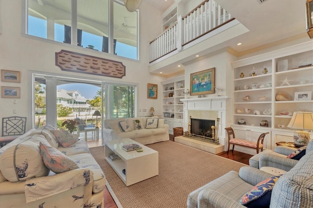 living room with a tile fireplace, hardwood / wood-style floors, and built in shelves