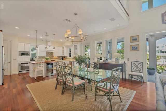 dining space featuring wine cooler, sink, an inviting chandelier, crown molding, and dark hardwood / wood-style flooring