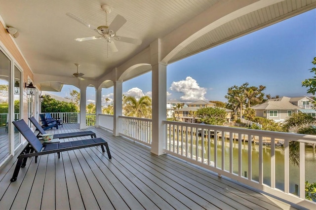 wooden terrace with a water view and ceiling fan