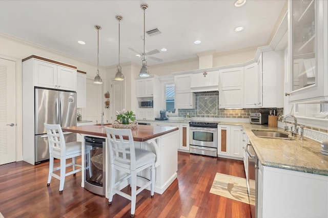 kitchen featuring wine cooler, decorative light fixtures, appliances with stainless steel finishes, a kitchen island, and white cabinets