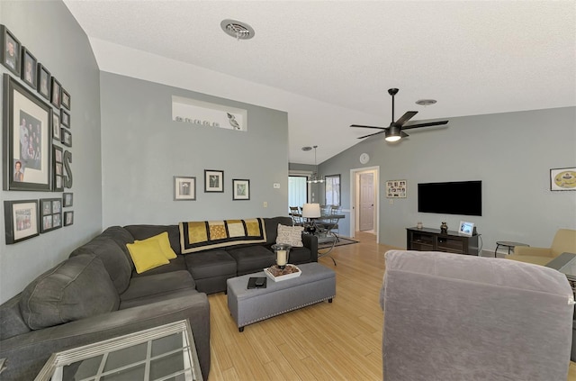 living room featuring ceiling fan, lofted ceiling, light hardwood / wood-style flooring, and a textured ceiling